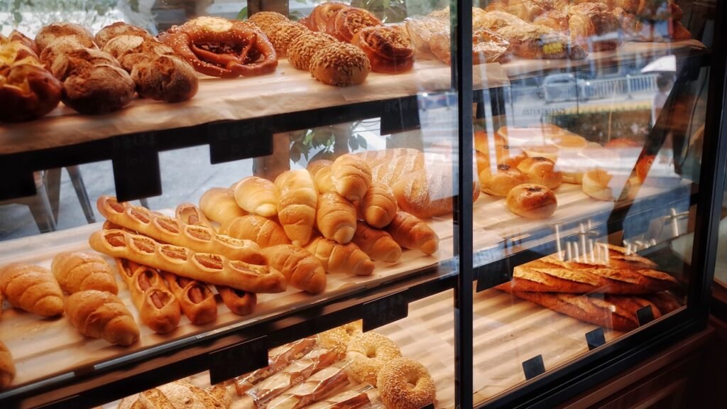 How to Start a Home Bakery Business in Gujarat: The Complete 2026 Guide 3 A well-stocked bakery display case filled with fresh breads, croissants, and pastries arranged on wooden shelves
