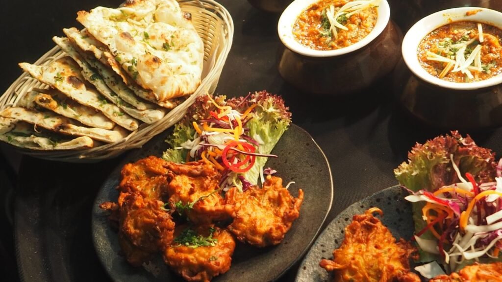 Gujarat's Vegetarian Food Heritage: Why It Leads India 9 A vibrant spread of traditional Indian vegetarian dishes including curries, flatbreads, and fried snacks arranged on a dark surface.