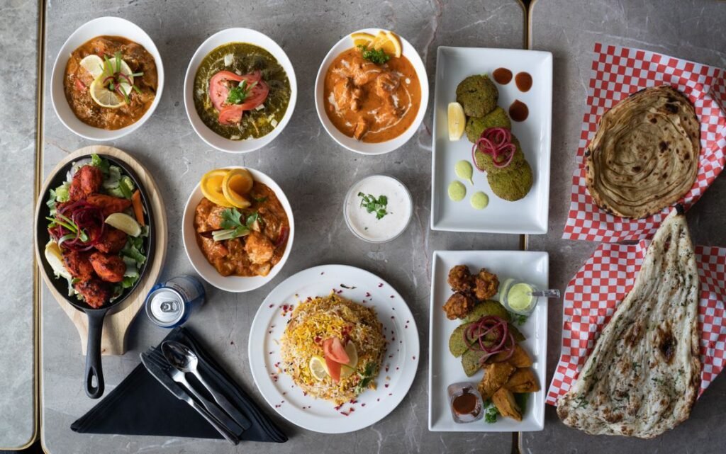 Indian Regional Cuisines You Can Learn to Cook in Ahmedabad 4 A diverse selection of Indian dishes beautifully arranged in an overhead flat-lay view, representing regional variety.