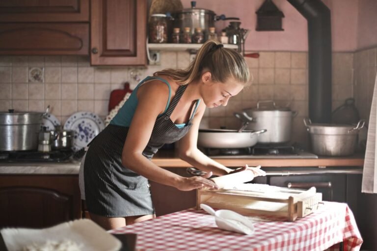 A young woman rolling dough for baking in a bright home kitchen — representing home bakers in Gujarat starting their food business.
