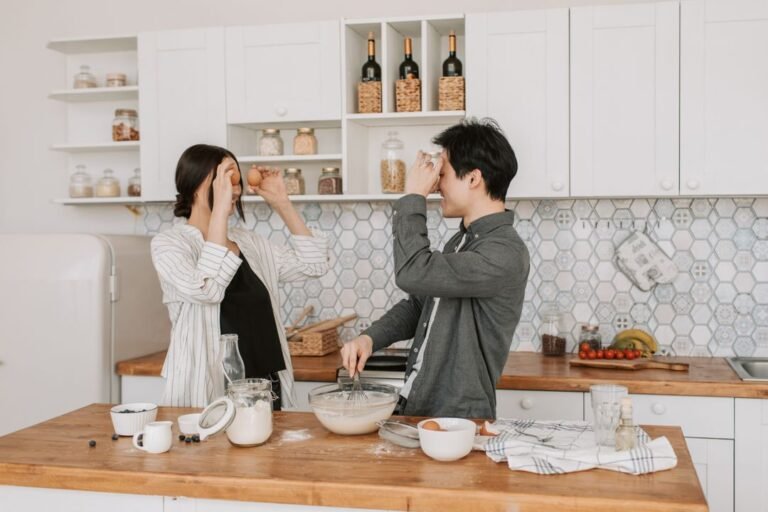 Two people baking together in a bright home kitchen, mixing batter in a bowl surrounded by baking tools and ingredients, representing affordable home bakery setup in India.