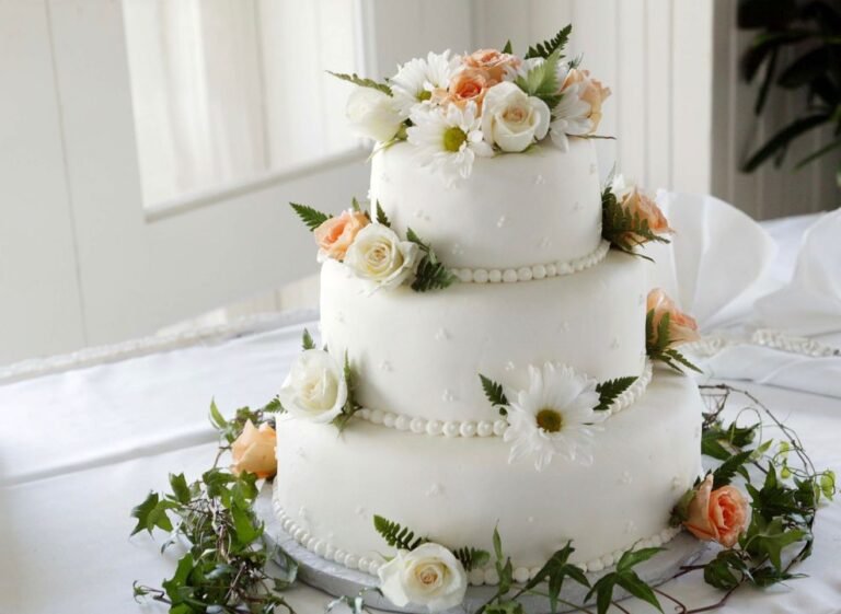 Elegant multi-tiered wedding cake with floral decorations on a white table
