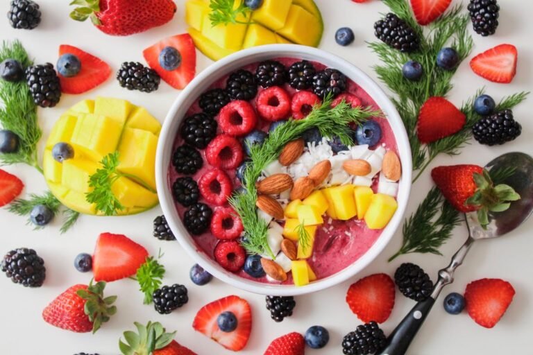 Colourful smoothie bowl with fresh fruit toppings granola and chia seeds on white bowl
