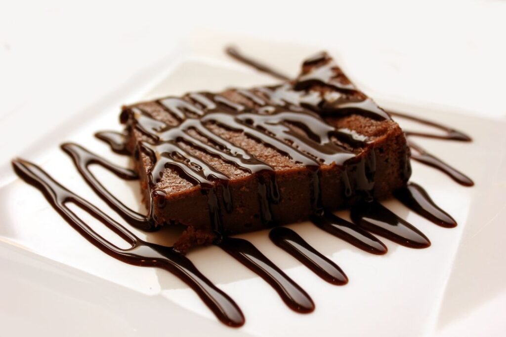 A tray of freshly baked chocolate brownies cut into squares with a crinkly top, sitting on a wooden board.