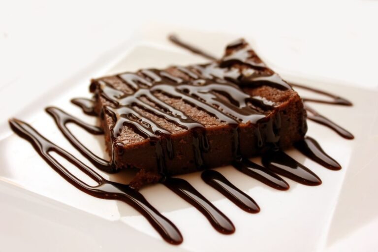 A tray of freshly baked chocolate brownies cut into squares with a crinkly top, sitting on a wooden board.