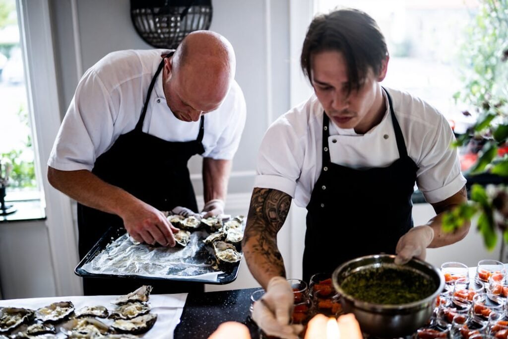 How to Get Placed at ITC Hotels, Marriott, and Top Gujarat Restaurants After a Culinary Course 6 Two professional chefs in white uniforms collaborating on plating a dish in a busy five-star hotel kitchen.