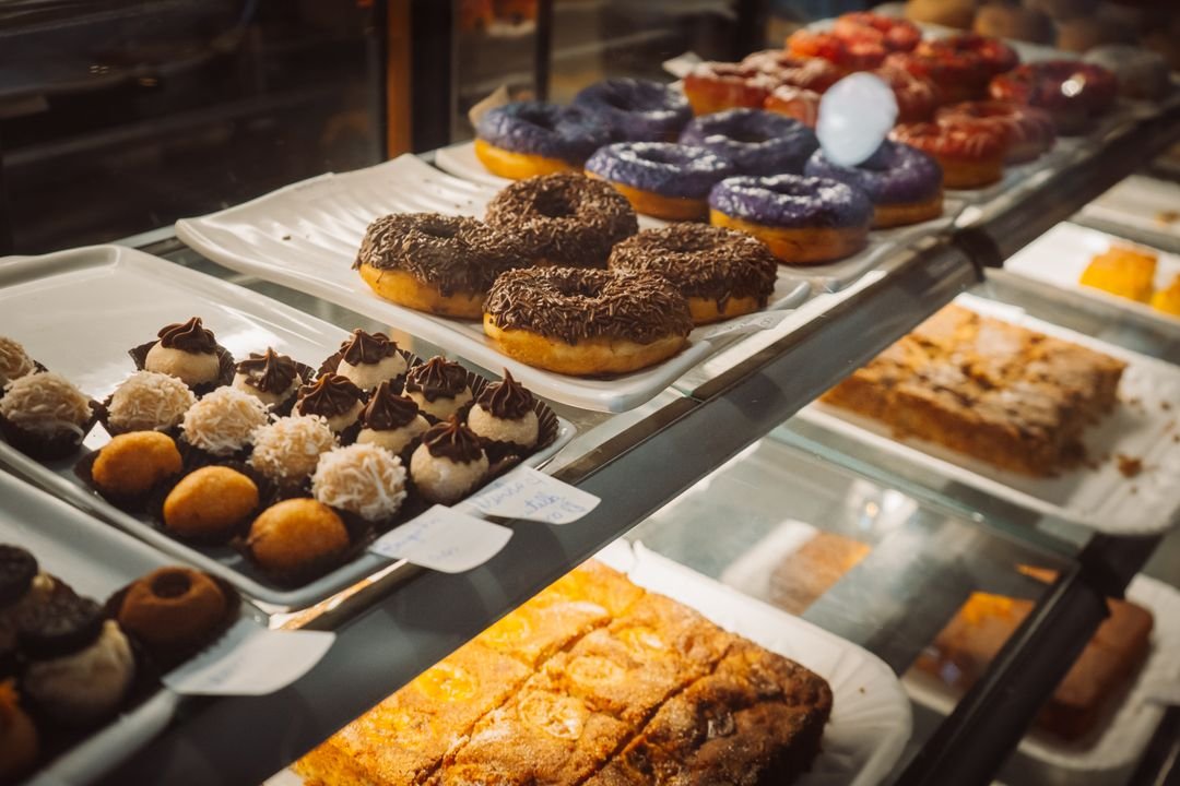 Assorted glazed doughnuts and filled pastries in a bakery display case