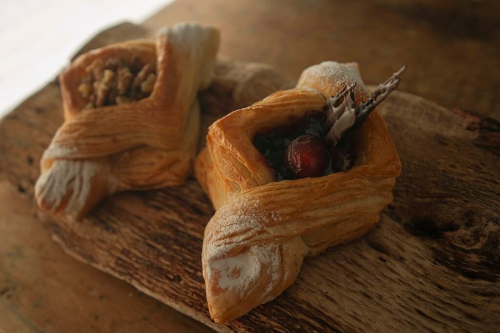 Rustic Danish pastries filled with fruit and nuts arranged on a wooden board.