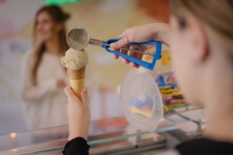 Scoop of ice cream being served onto a waffle cone