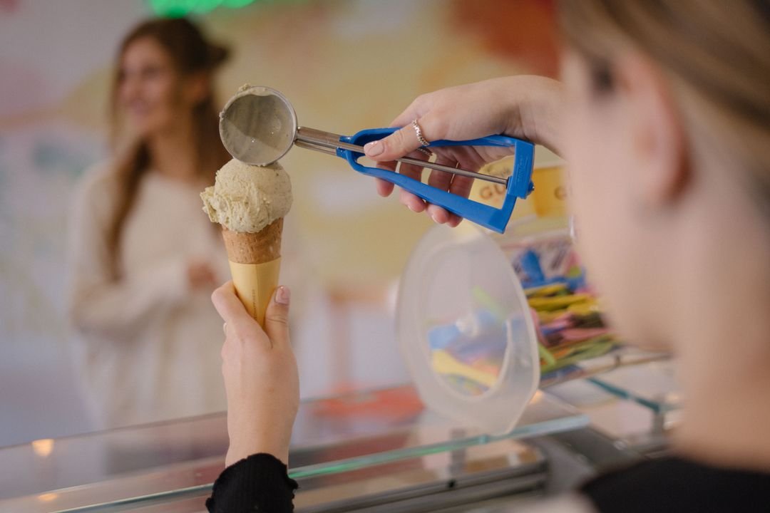 Scoop of ice cream being served onto a waffle cone