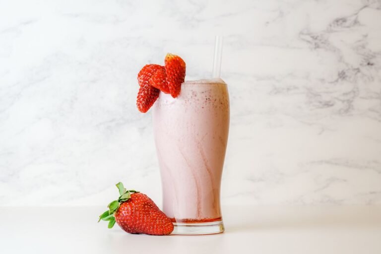 Creamy strawberry milkshake topped with fresh strawberry garnish