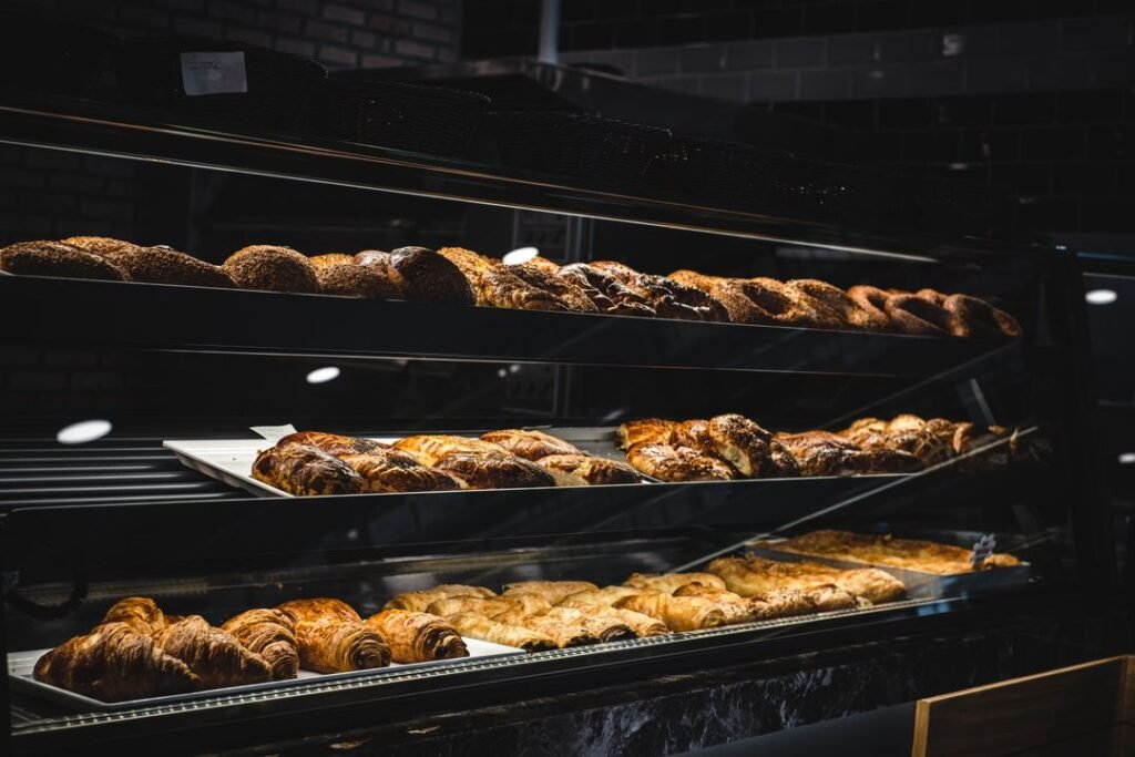 A glass bakery display case filled with freshly baked breads and pastries ready for cafe service.