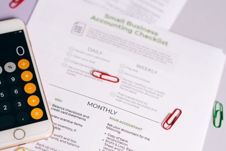 A checklist, calculator and accounting documents laid out on a desk, representing the paperwork behind a home bakery business.
