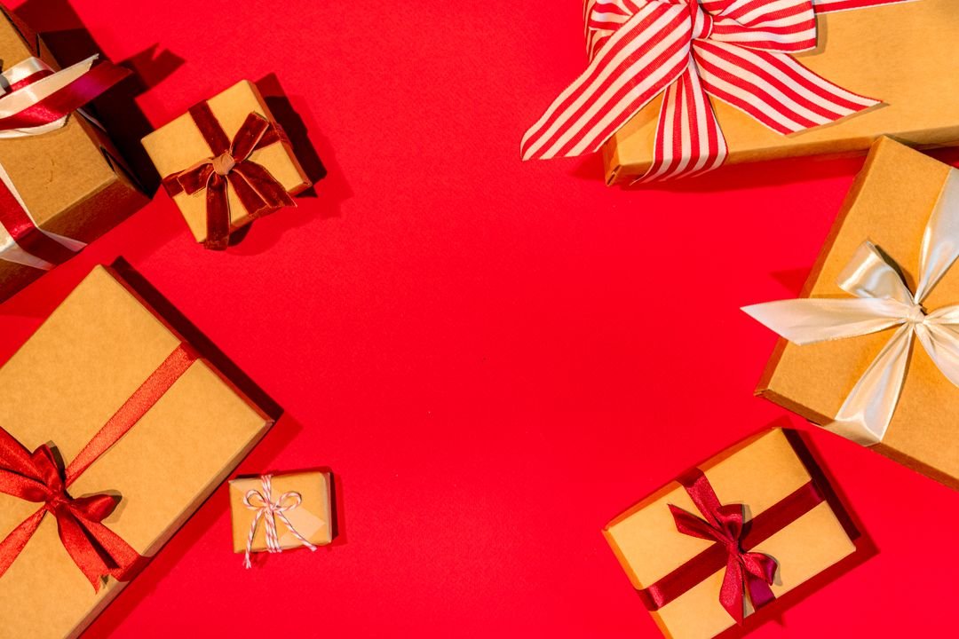 Overhead shot of festival gift boxes being arranged with ribbons and kraft packaging on a wooden table