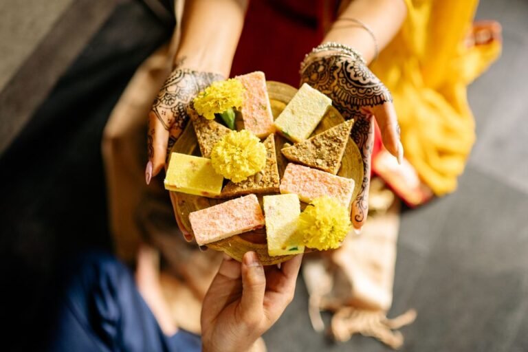 Traditional Indian sweets arranged with marigold flowers for a festival offering.