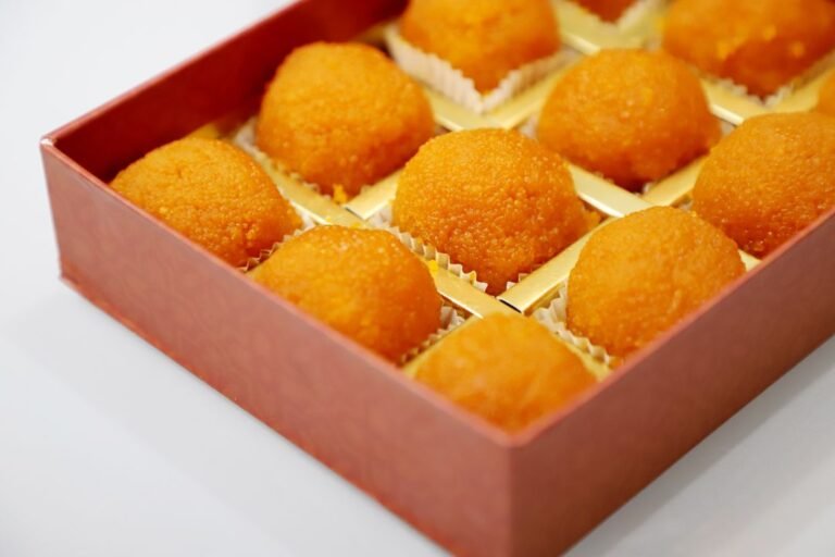Freshly made laddoos arranged in a decorative box for a festival celebration.