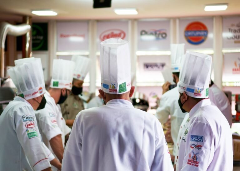 A team of professional chefs in white uniforms working together in a hotel kitchen.