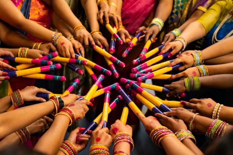 A circle of hands holding colourful dandiya sticks together during a Navratri garba celebration.