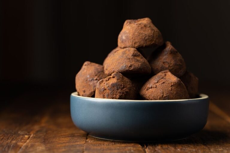 A bowl of cocoa-dusted chocolate truffle balls, similar in shape to hand-rolled chocolate modak.